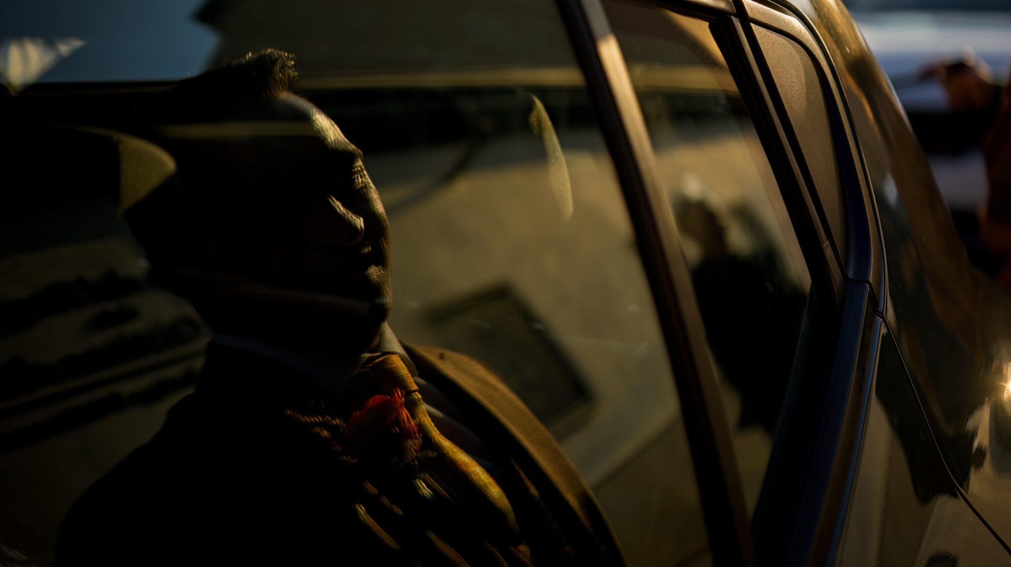 Reflejo del novio en la ventanilla del coche con luz cálida de atardecer